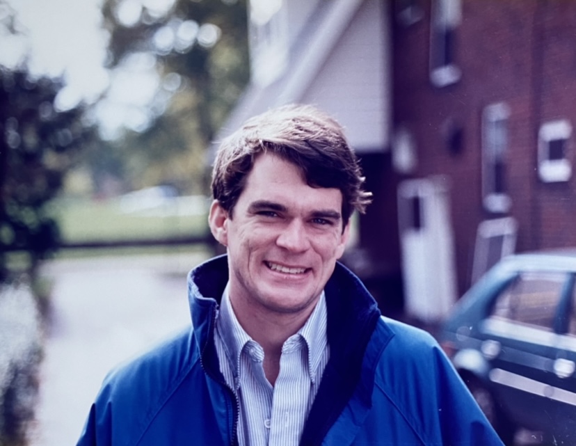 A man in a blue jacket smiling for the camera.