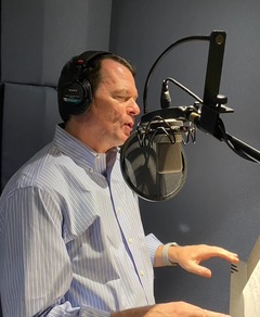 A man with headphones is singing into a microphone.